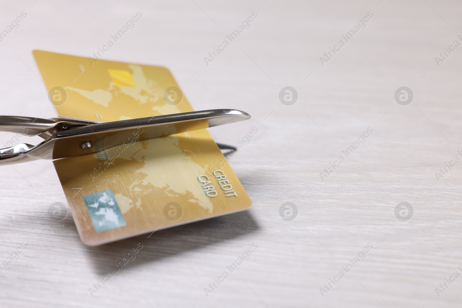 Photo of Credit card and scissors on white wooden table, closeup. Space for text