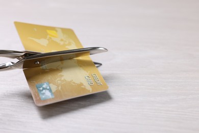 Photo of Credit card and scissors on white wooden table, closeup. Space for text