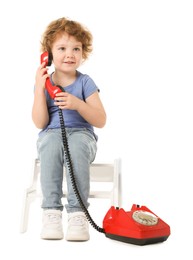 Photo of Cute little boy with telephone on step stool against white background