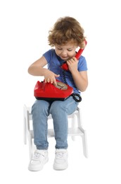 Photo of Cute little boy with telephone on step stool against white background