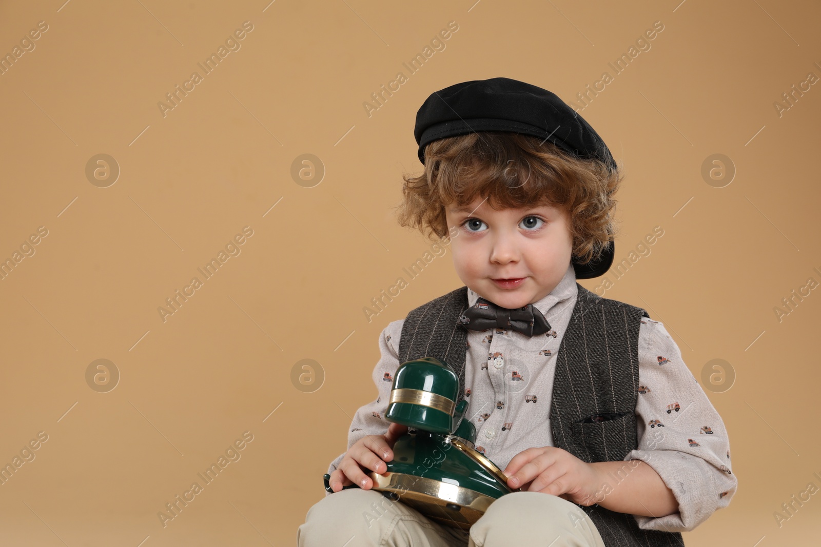 Photo of Cute little boy with old telephone on beige background, space for text