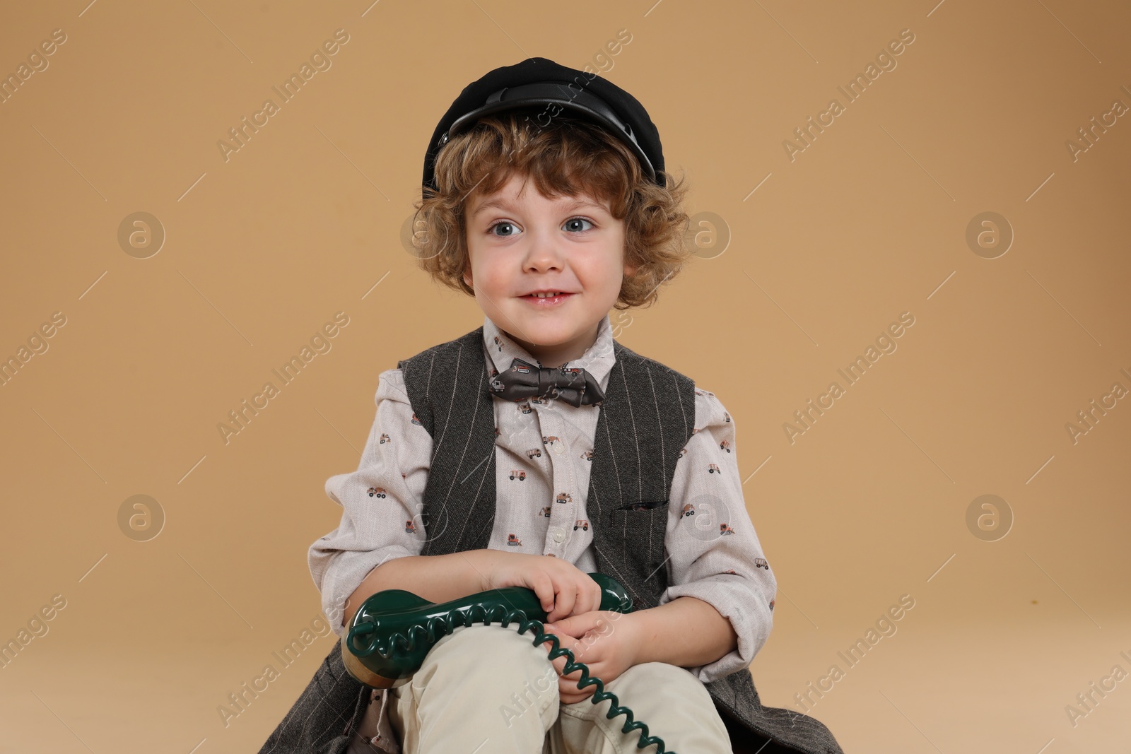 Photo of Cute little boy with telephone handset on beige background