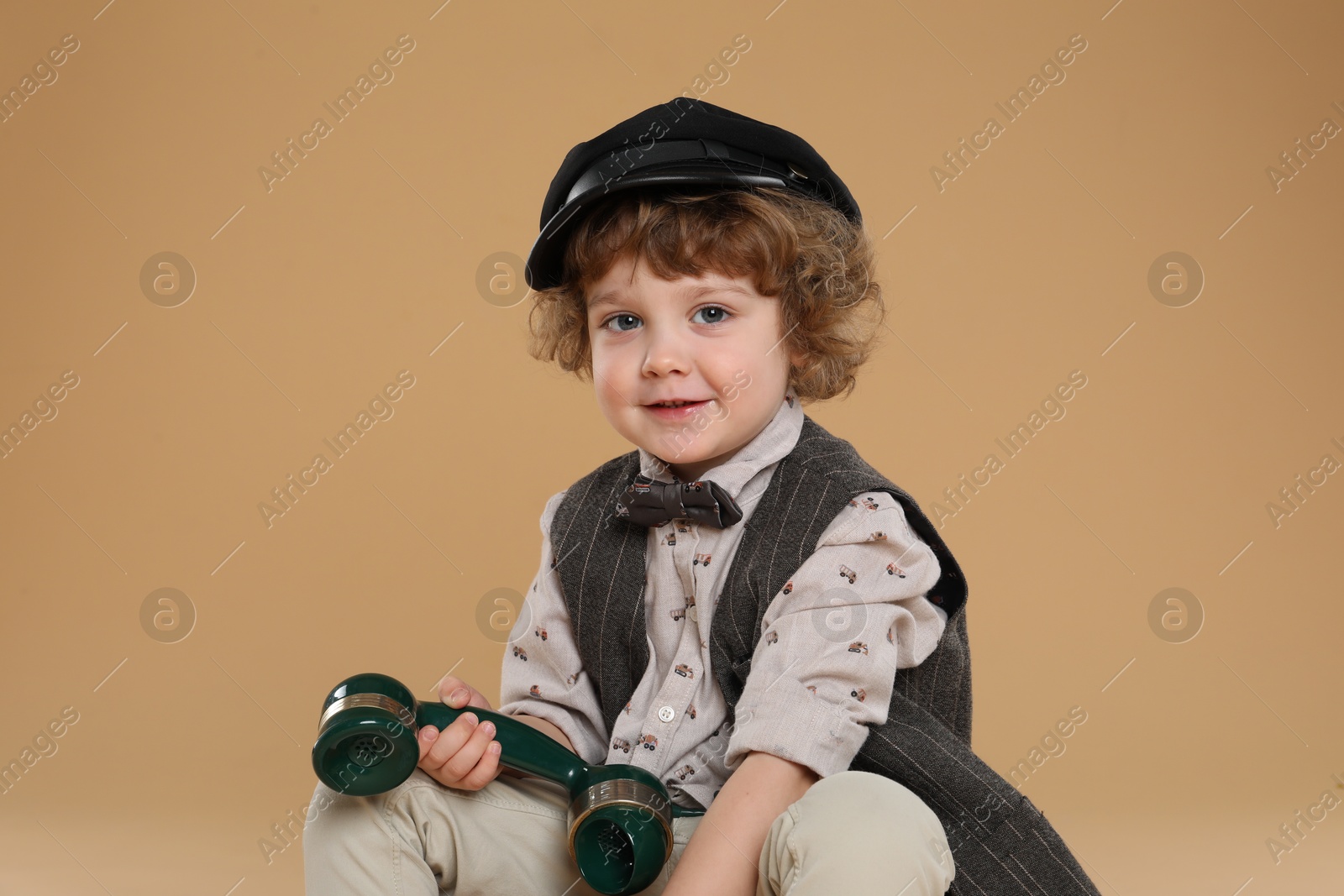 Photo of Cute little boy with telephone handset on beige background