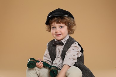 Cute little boy with telephone handset on beige background