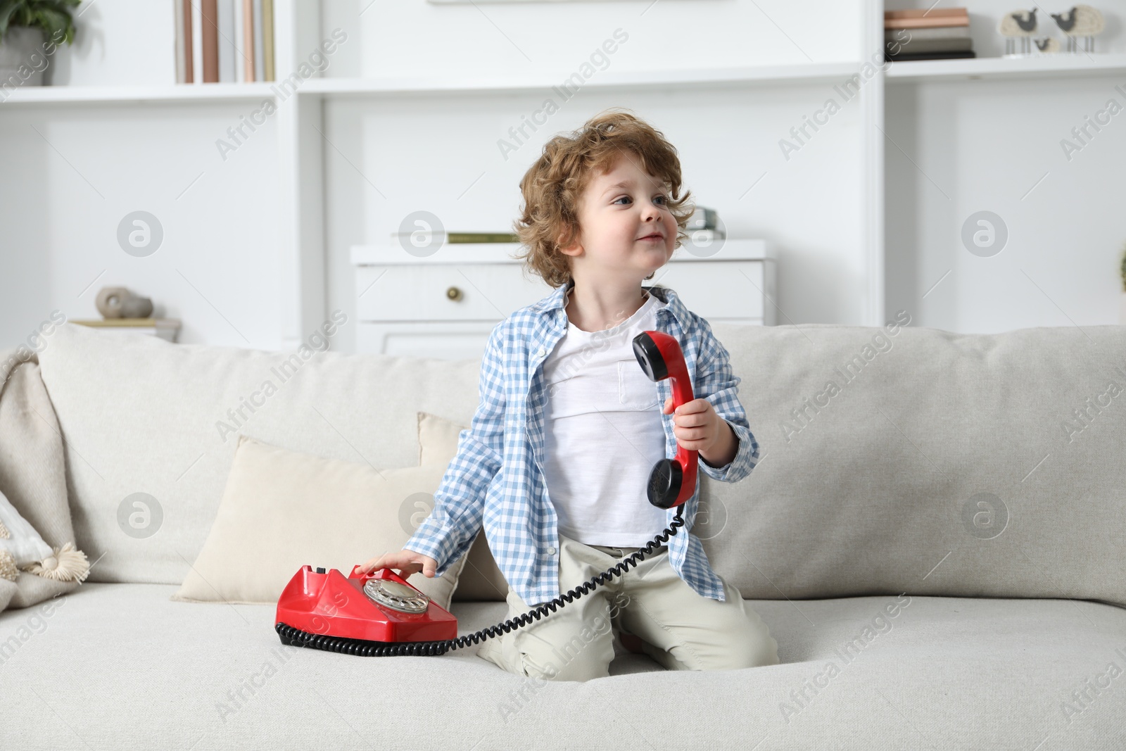 Photo of Cute little boy with telephone on sofa indoors