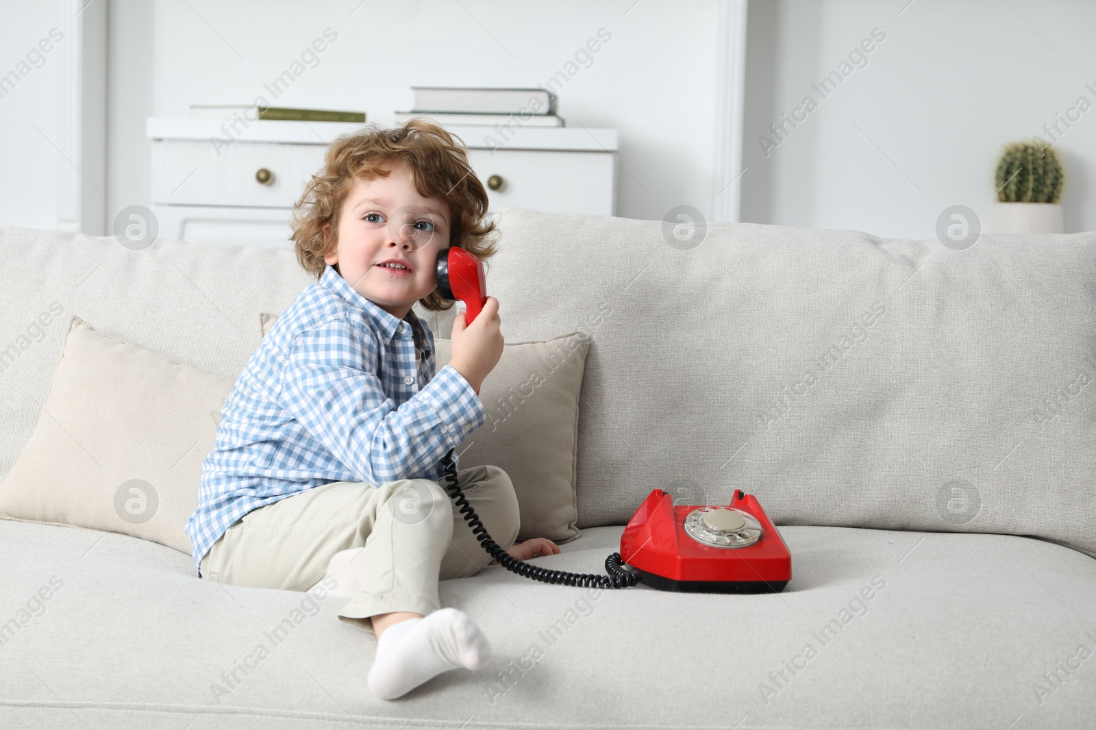 Photo of Cute little boy with telephone on sofa indoors