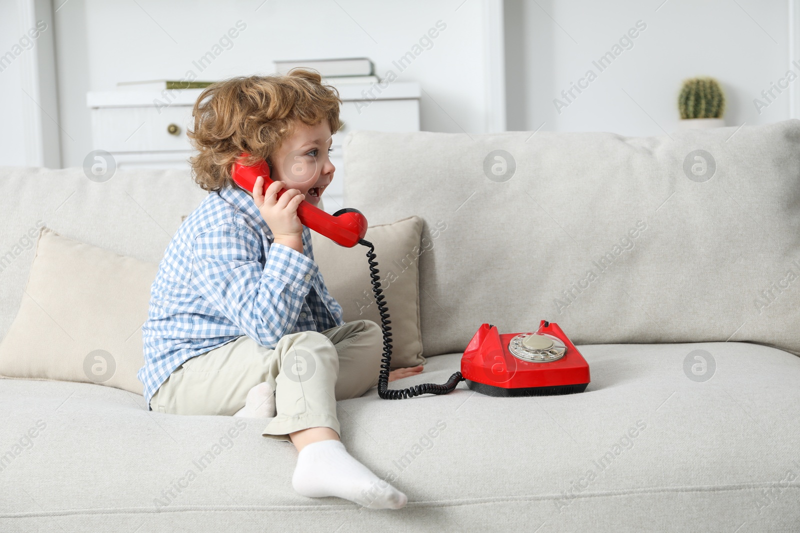 Photo of Cute little boy with telephone on sofa indoors