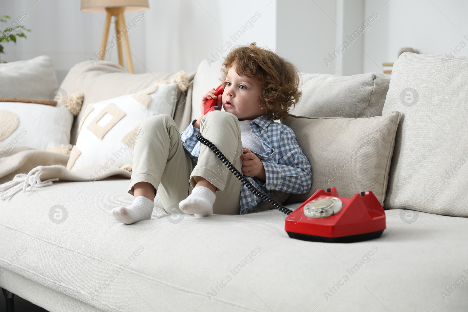 Photo of Cute little boy with telephone on sofa indoors