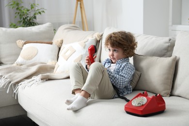 Photo of Cute little boy with telephone on sofa indoors