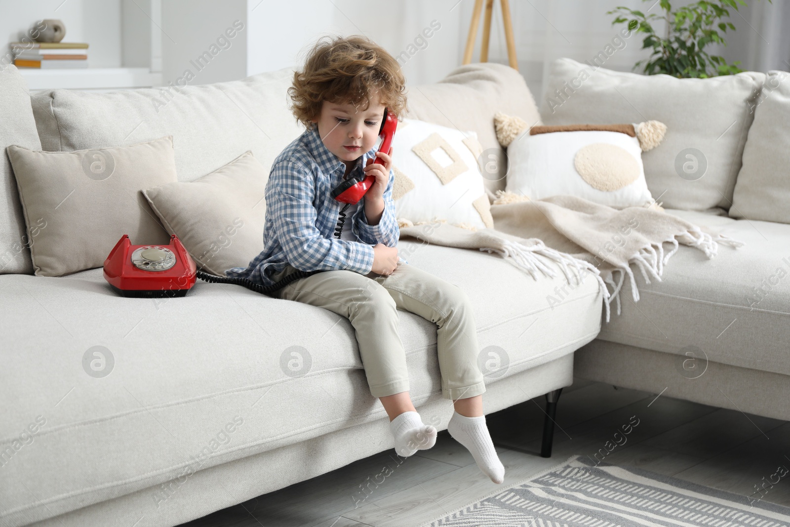 Photo of Cute little boy with telephone on sofa indoors