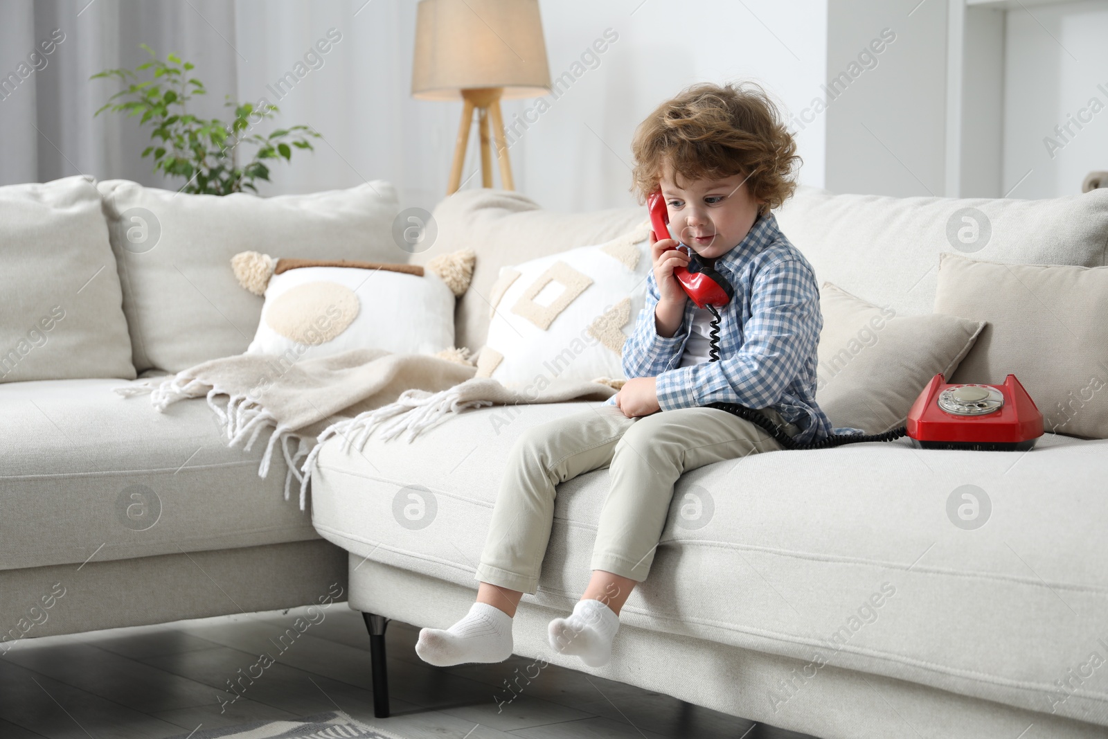 Photo of Cute little boy with telephone on sofa indoors