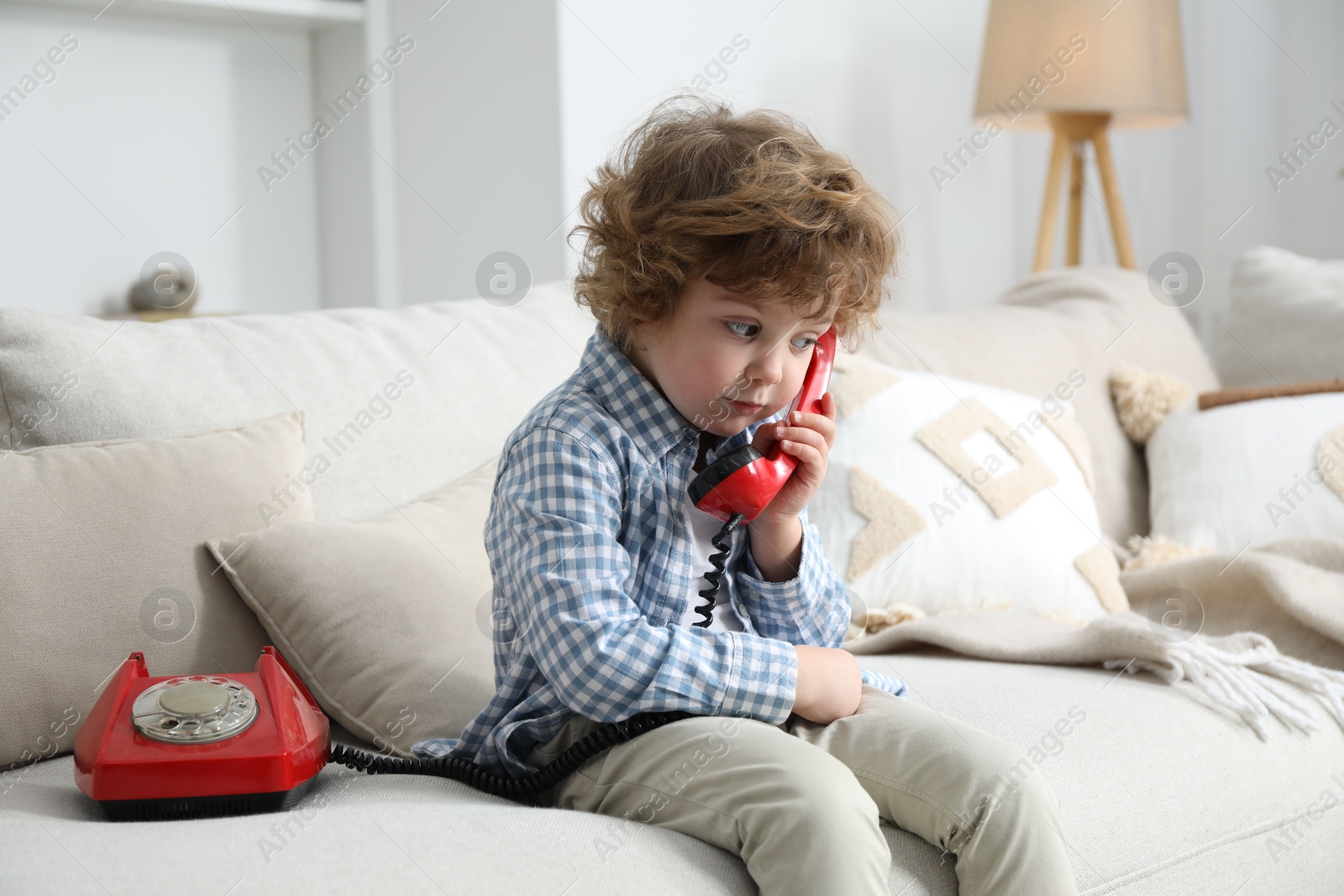 Photo of Cute little boy with telephone on sofa indoors