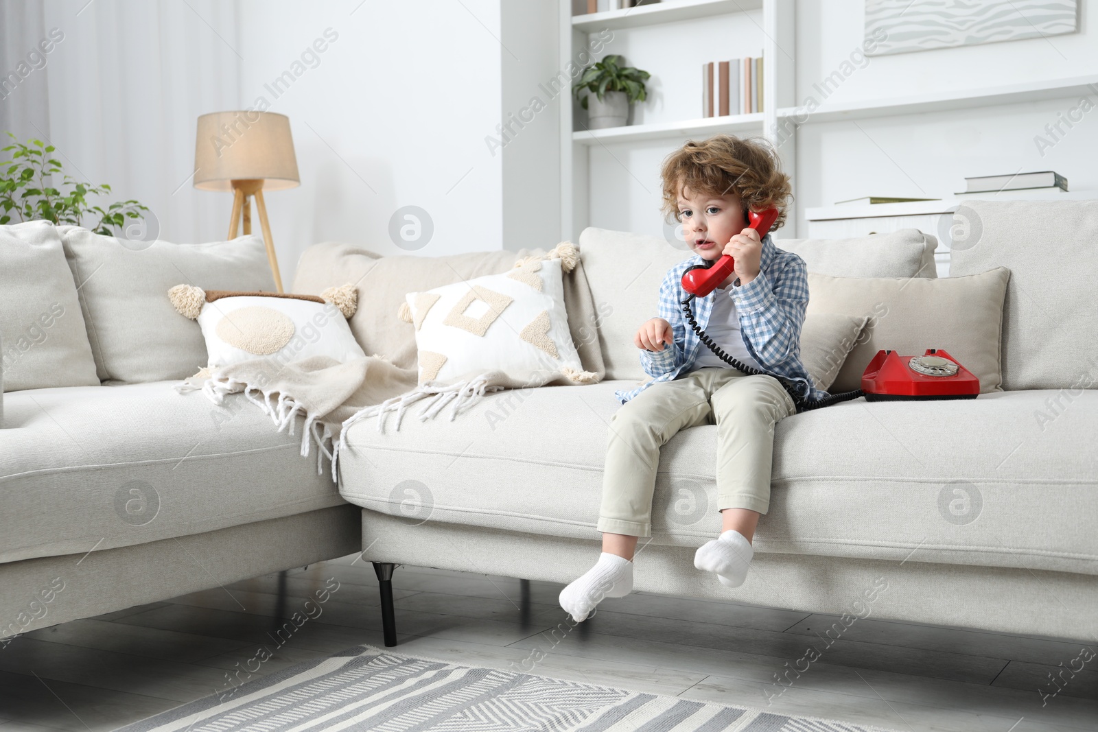 Photo of Cute little boy with telephone on sofa indoors