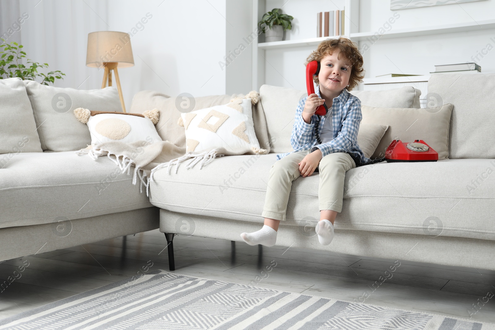 Photo of Cute little boy with telephone on sofa indoors