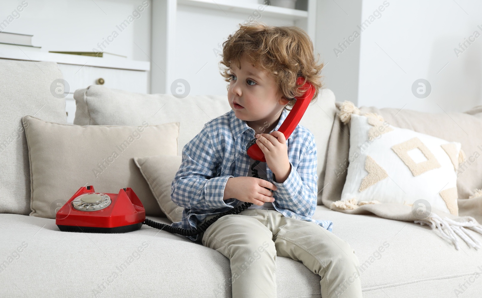 Photo of Cute little boy with telephone on sofa indoors