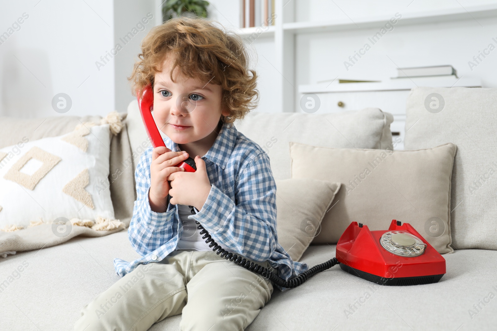 Photo of Cute little boy with telephone on sofa indoors