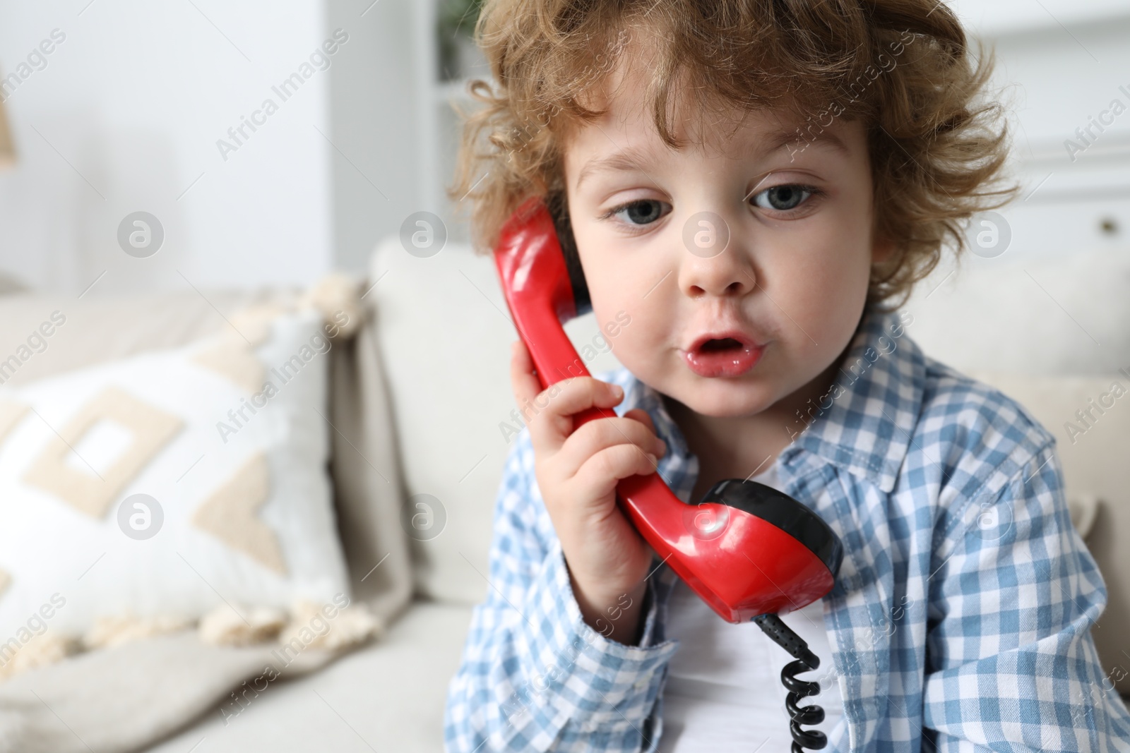 Photo of Cute little boy with telephone handset on sofa indoors, space for text