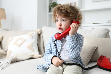 Photo of Cute little boy with telephone on sofa indoors