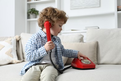 Photo of Cute little boy with telephone on sofa indoors