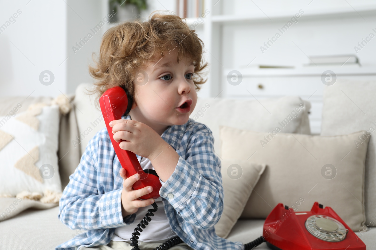 Photo of Cute little boy with telephone on sofa indoors