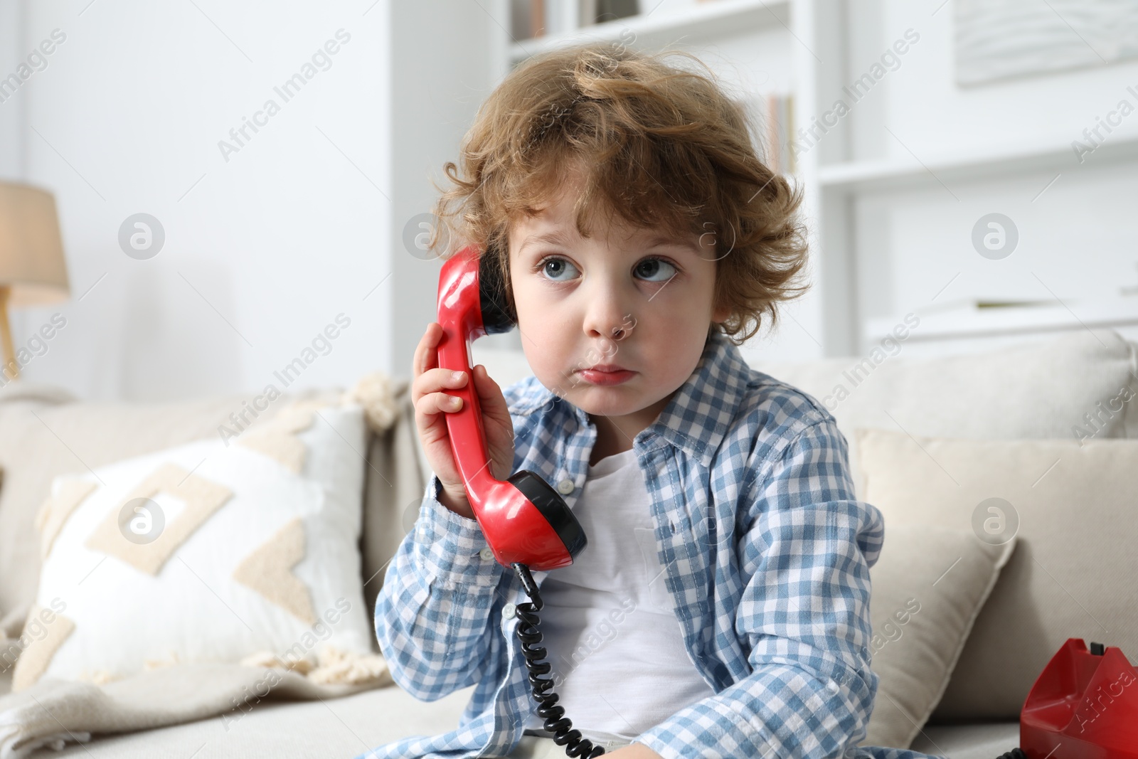 Photo of Cute little boy with telephone on sofa indoors