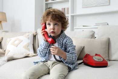 Photo of Cute little boy with telephone on sofa indoors