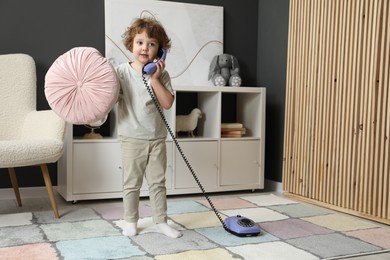 Photo of Cute little boy with telephone at home