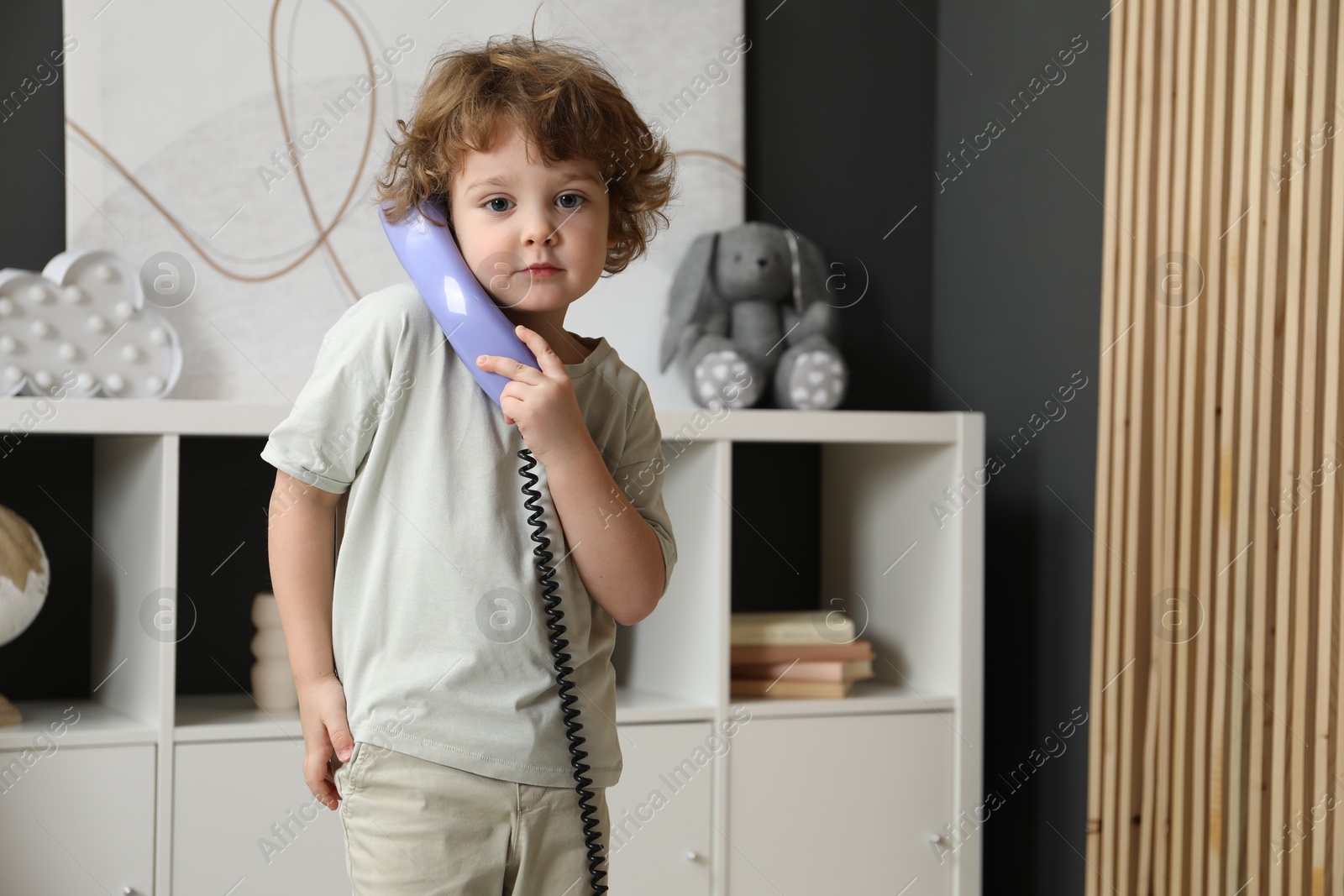 Photo of Cute little boy with telephone handset indoors, space for text