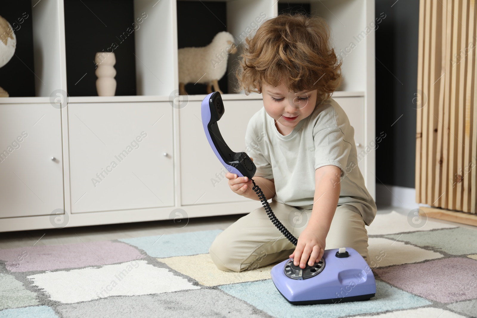 Photo of Cute little boy with telephone on floor indoors, space for text