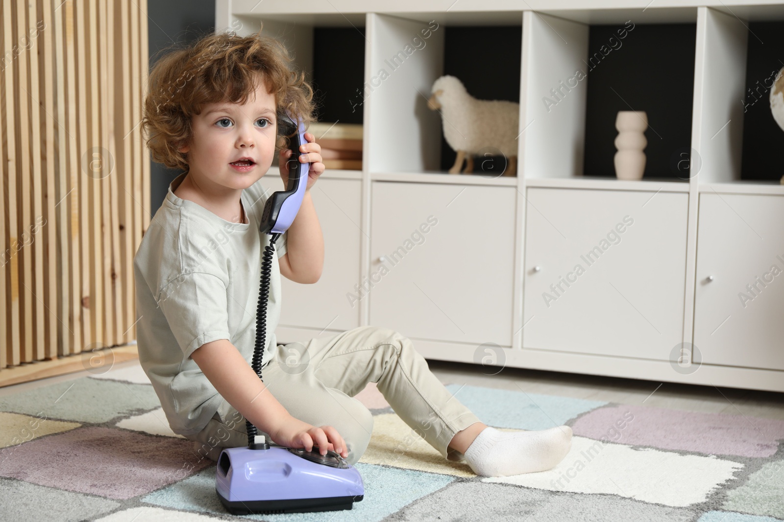 Photo of Cute little boy with telephone on floor indoors, space for text