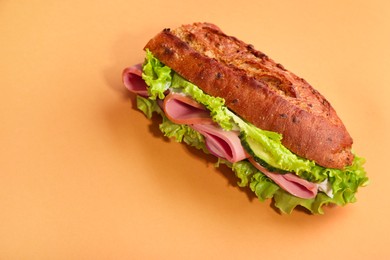 Photo of Baguette sandwich with ham on orange background. Space for text