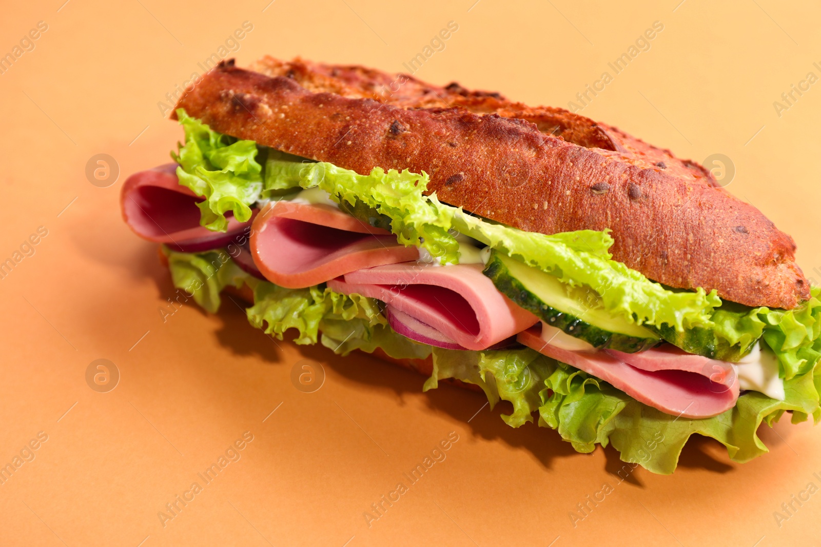 Photo of Baguette sandwich with ham on orange background, closeup