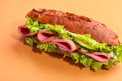 Photo of Baguette sandwich with ham on orange background, closeup