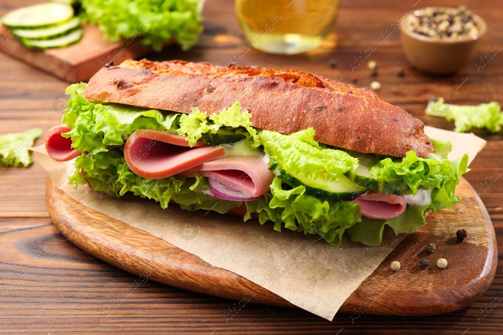 Photo of Delicious baguette sandwich with ham on wooden table, closeup