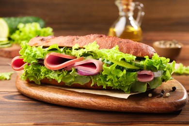 Photo of Delicious baguette sandwich with ham on wooden table, closeup