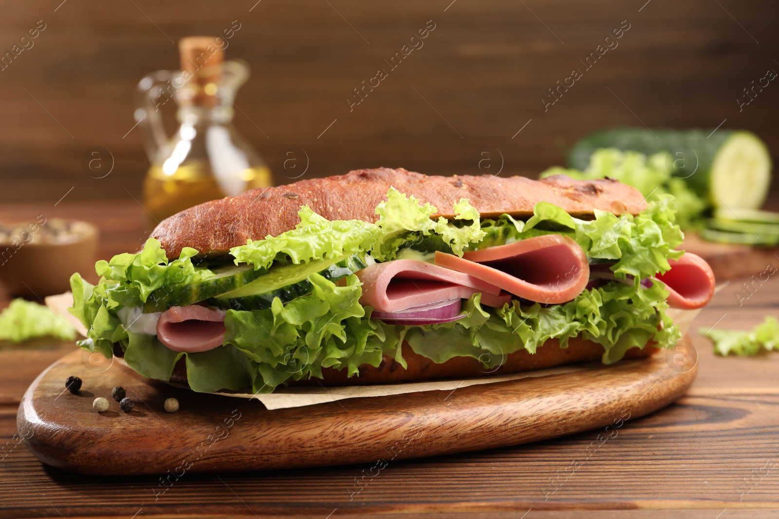 Photo of Delicious baguette sandwich with ham on wooden table, closeup