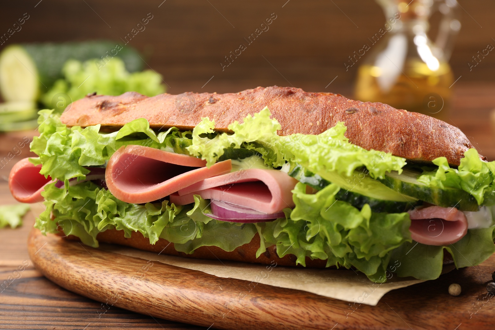 Photo of Delicious baguette sandwich with ham on wooden table, closeup