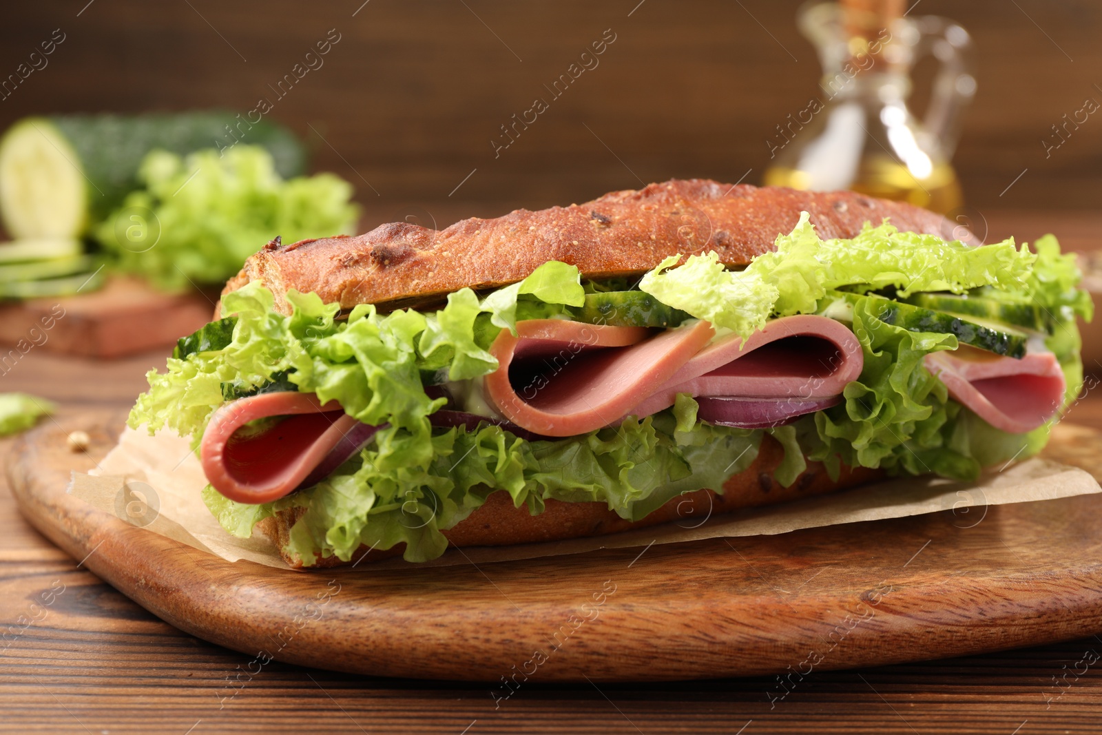 Photo of Delicious baguette sandwich with ham on wooden table, closeup