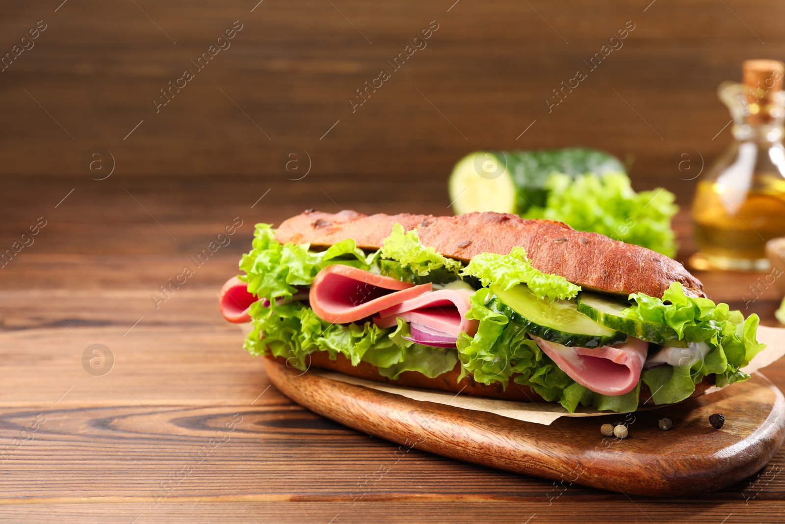 Photo of Delicious baguette sandwich with ham on wooden table. Space for text