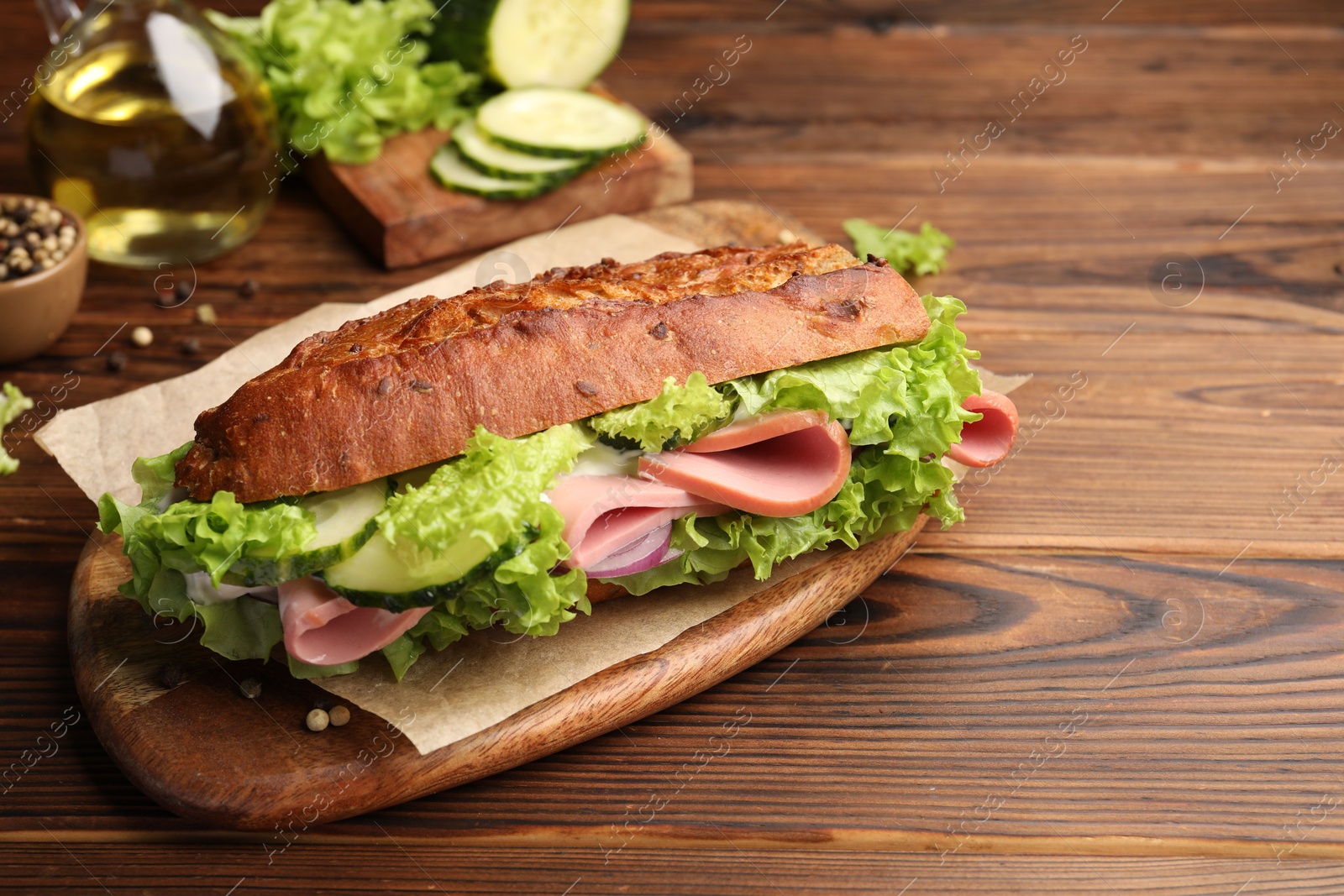 Photo of Delicious baguette sandwich with ham on wooden table