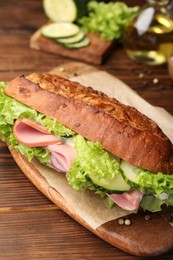 Photo of Delicious baguette sandwich with ham on wooden table, closeup