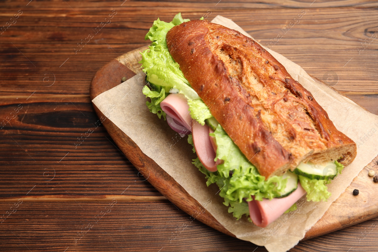 Photo of Delicious baguette sandwich with ham on wooden table, closeup