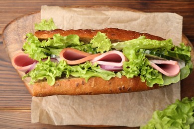 Photo of Delicious baguette sandwich with ham on wooden table, top view