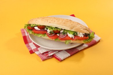 Photo of Delicious baguette with salmon on yellow background