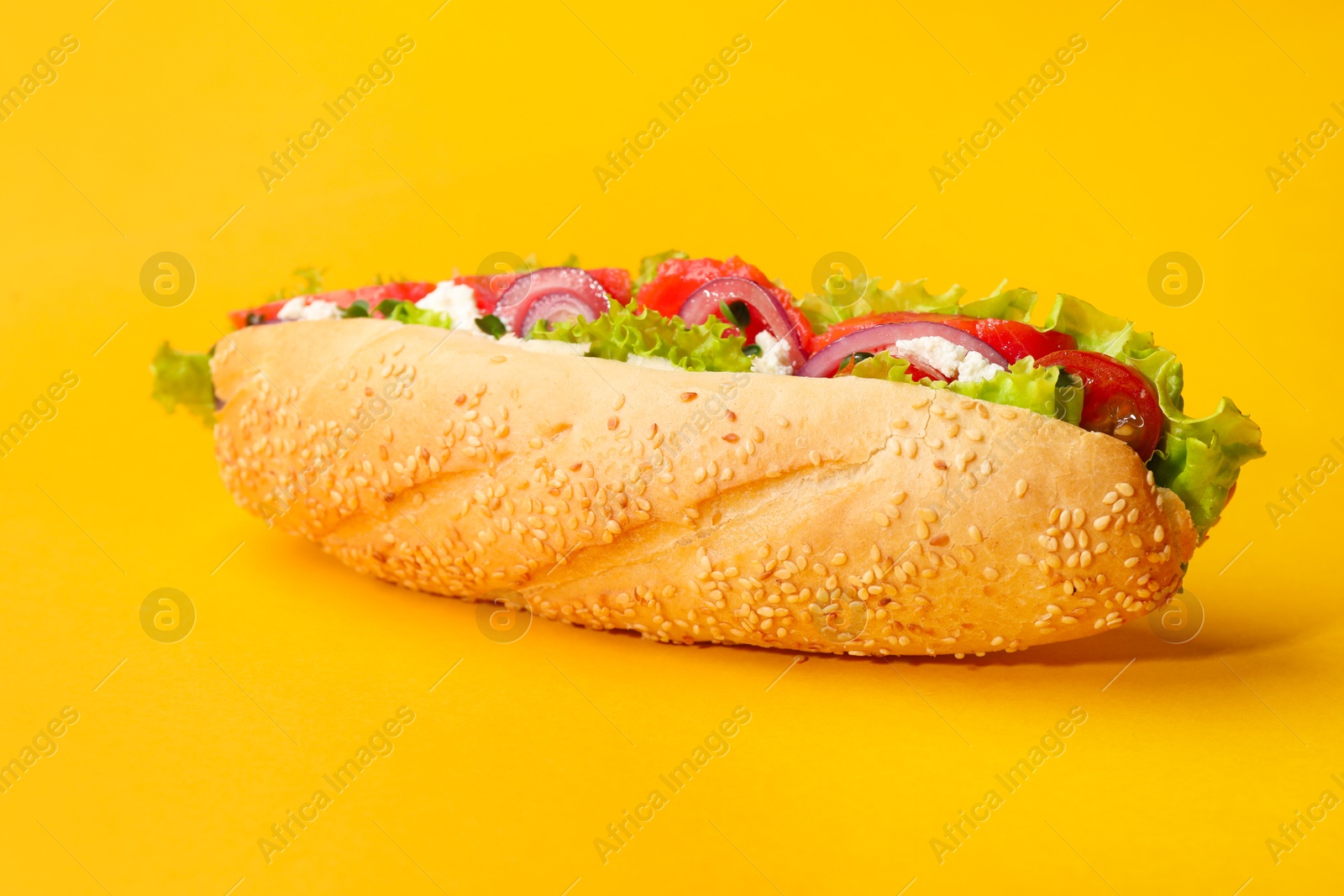 Photo of Delicious baguette with salmon on yellow background, closeup