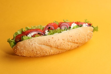 Photo of Delicious baguette with salmon on yellow background, closeup