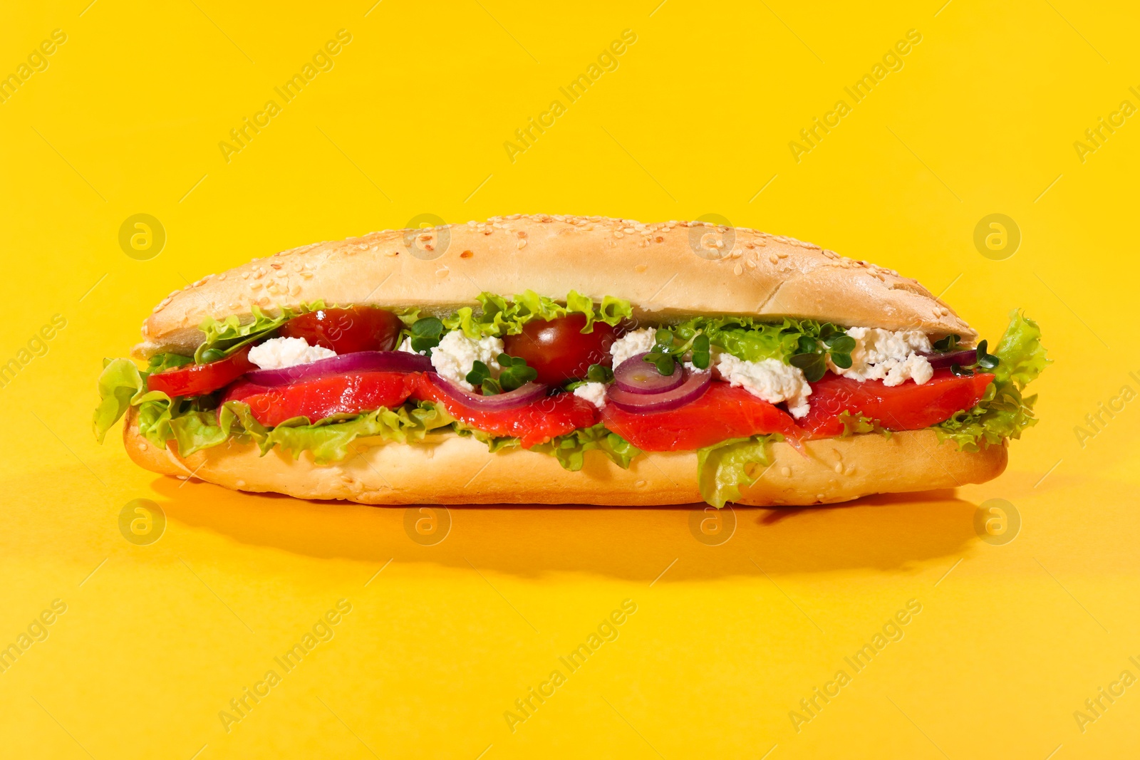 Photo of Delicious baguette with salmon on yellow background