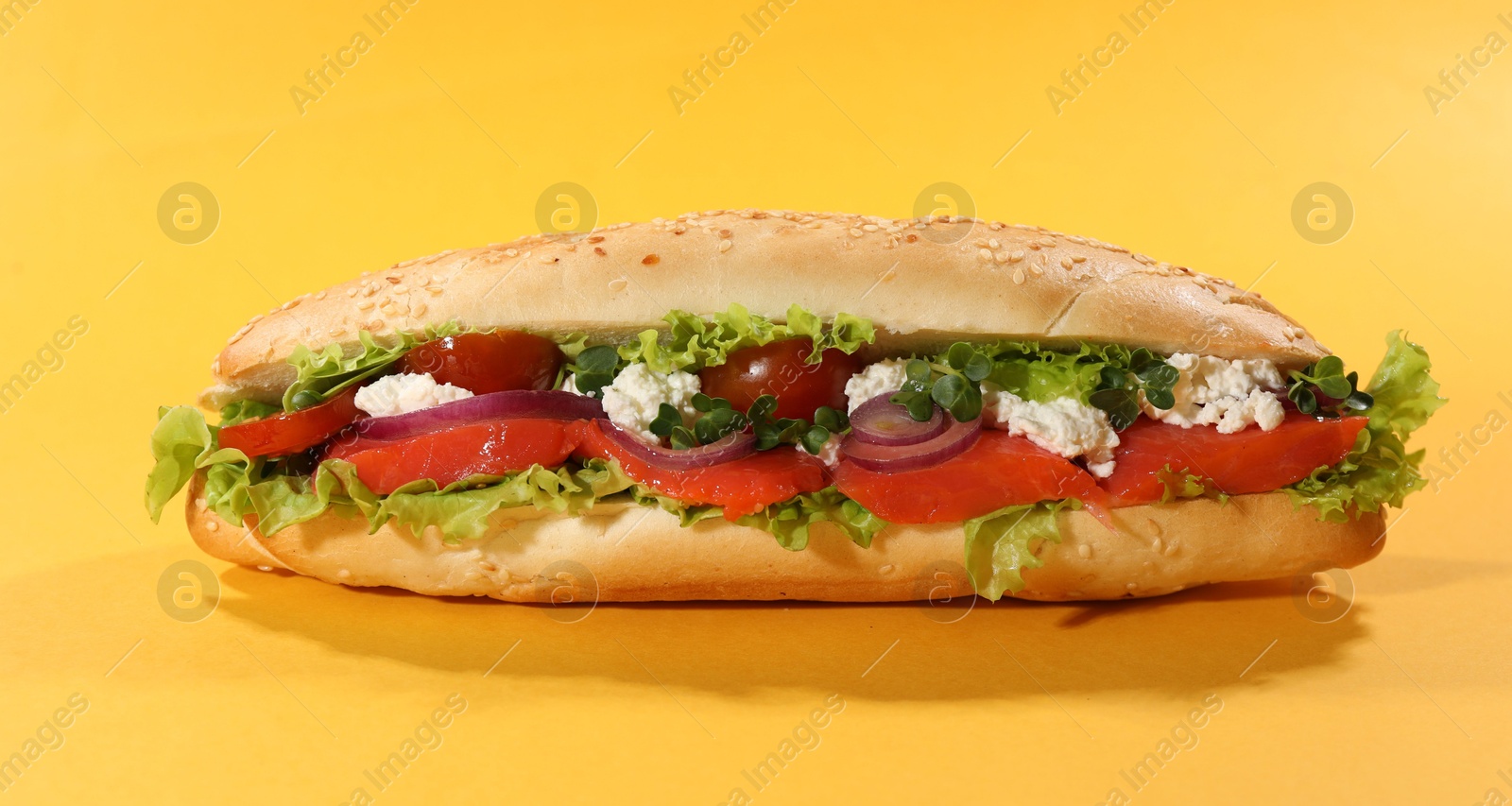 Photo of Delicious baguette with salmon on yellow background, closeup