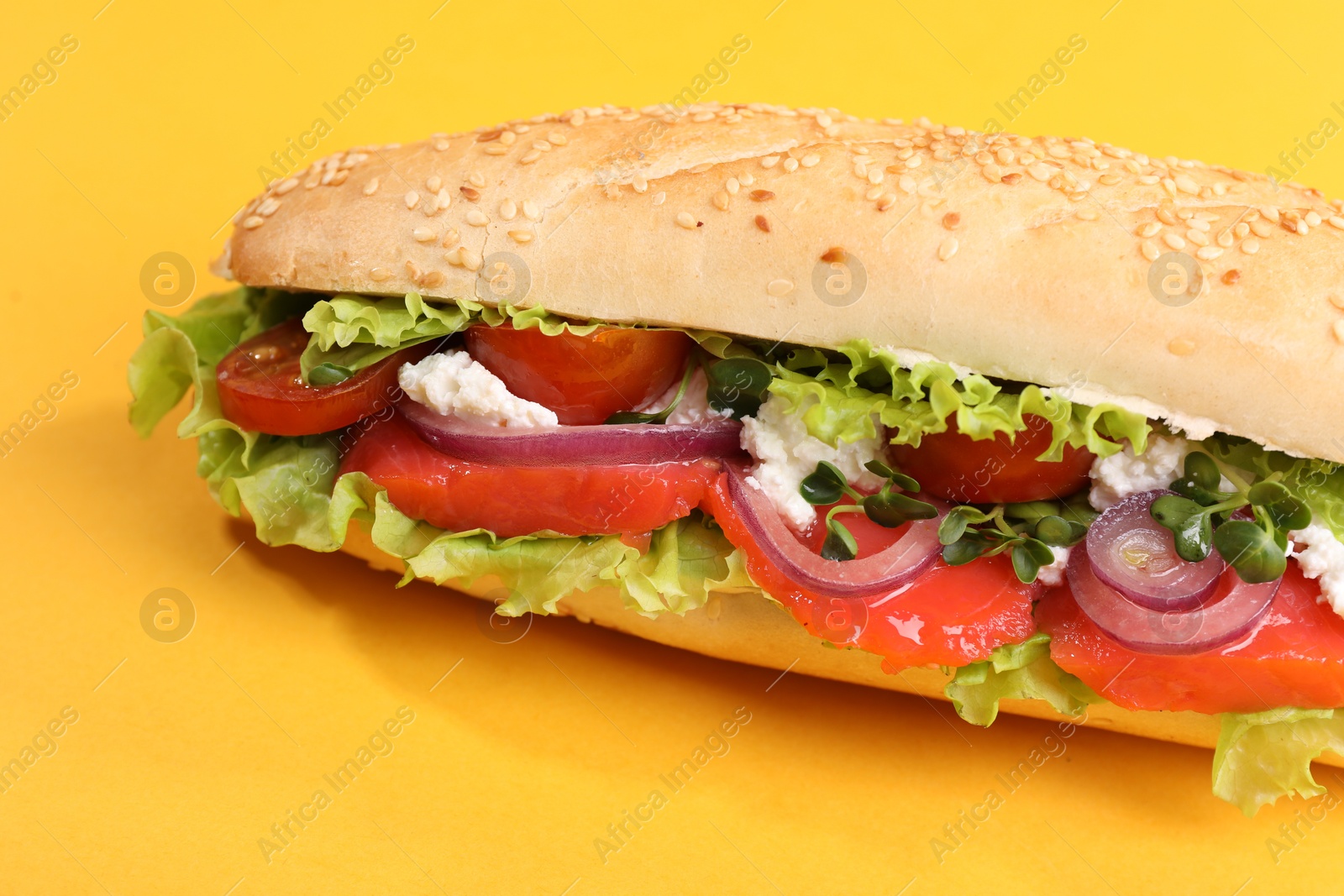 Photo of Delicious baguette with salmon on yellow background, closeup