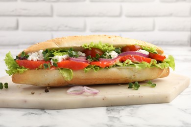 Photo of Delicious baguette with salmon on white marble table, closeup